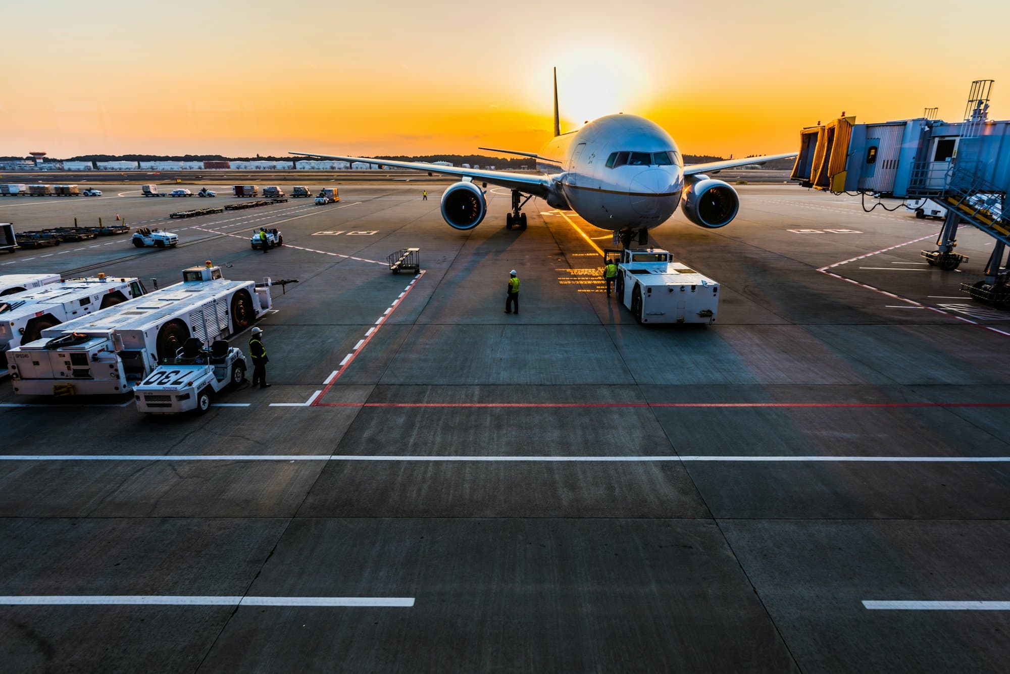 Aircraft and ground crew on an airport apron at sunset
