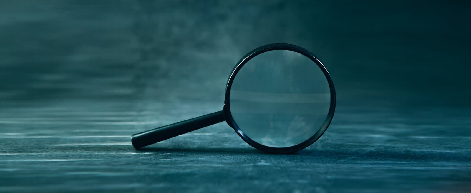 Magnifying glass on a dark teal surface