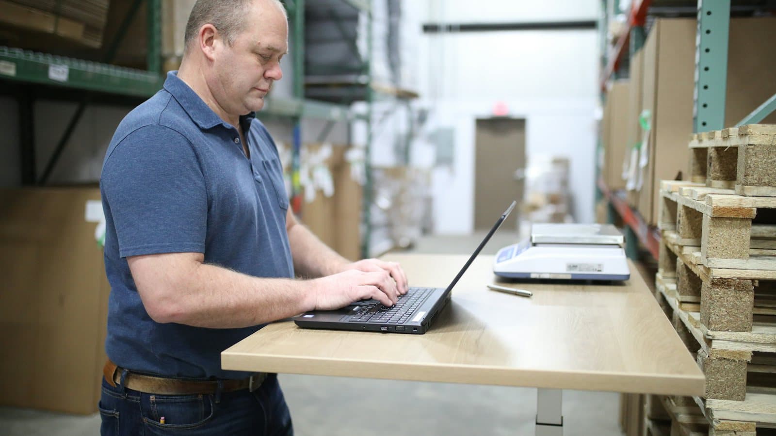 Person working on a laptop in a warehouse office